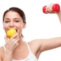 mulher se alimenta com uma fruta e faz exercício com peso