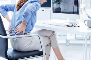Mulher com dor nas costas durante o trabalho no computador