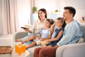 Uma família assistindo um filme na TV para relaxar e ajudar a aliviar o cansaço mental