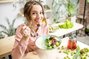 Mulher comendo alimentos que ajudam na saúde bucal