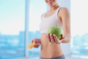 Uma mulher segurando uma maçã verde que uma das frutas de baixas calorias