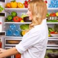 Uma mulher conferindo na geladeira as opções de como manter uma alimentação equilibrada
