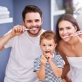 Uma família escovando os dentes para terem uma boa saúde bucal e qualidade de vida