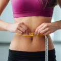 Uma mulher medindo a cintura sabendo que para emagrecer com saúde precisou mudar de hábitos