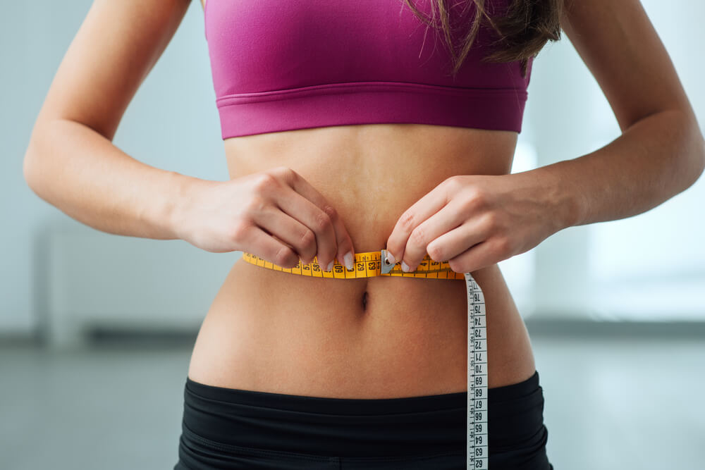 Uma mulher medindo a cintura sabendo que para emagrecer com saúde precisou mudar de hábitos