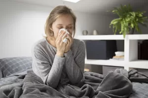Uma mulher de cama com sintomas de gripe