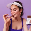 Uma mulher comendo chocolate amargo e aproveitando os benefícios do chocolate amargo para saúde