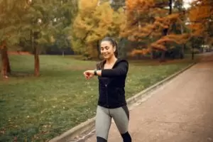 Uma mulher jovem praticando a caminhada japonesa num parque