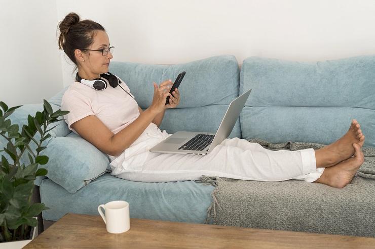 Uma mulher utilizando o celular e o notebook ao mesmo tempo e precisando praticar o detox digital.